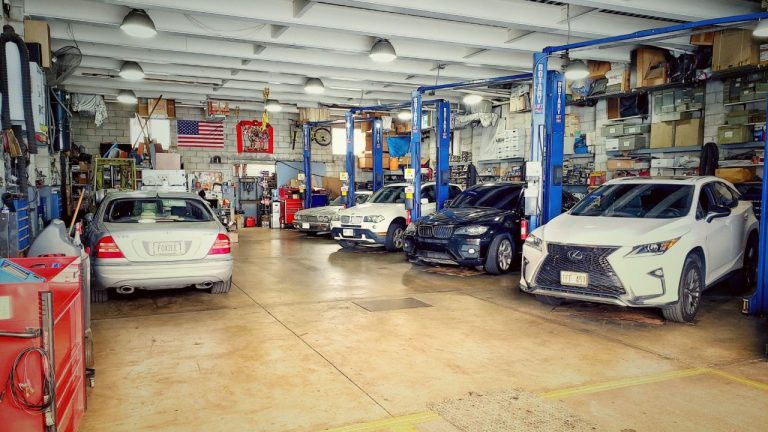 Busy automotive repair shop with multiple vehicles, lifts, tools, and equipment