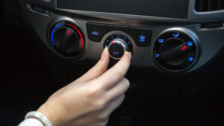 Car air-conditioning controls being adjusted inside a vehicle cabin