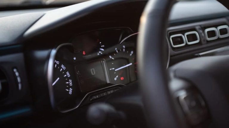 Car dashboard and instrument cluster displaying speed, gauges, and warning indicators