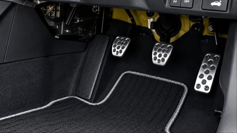 Car pedals and floor mat shown inside a vehicle’s driver footwell