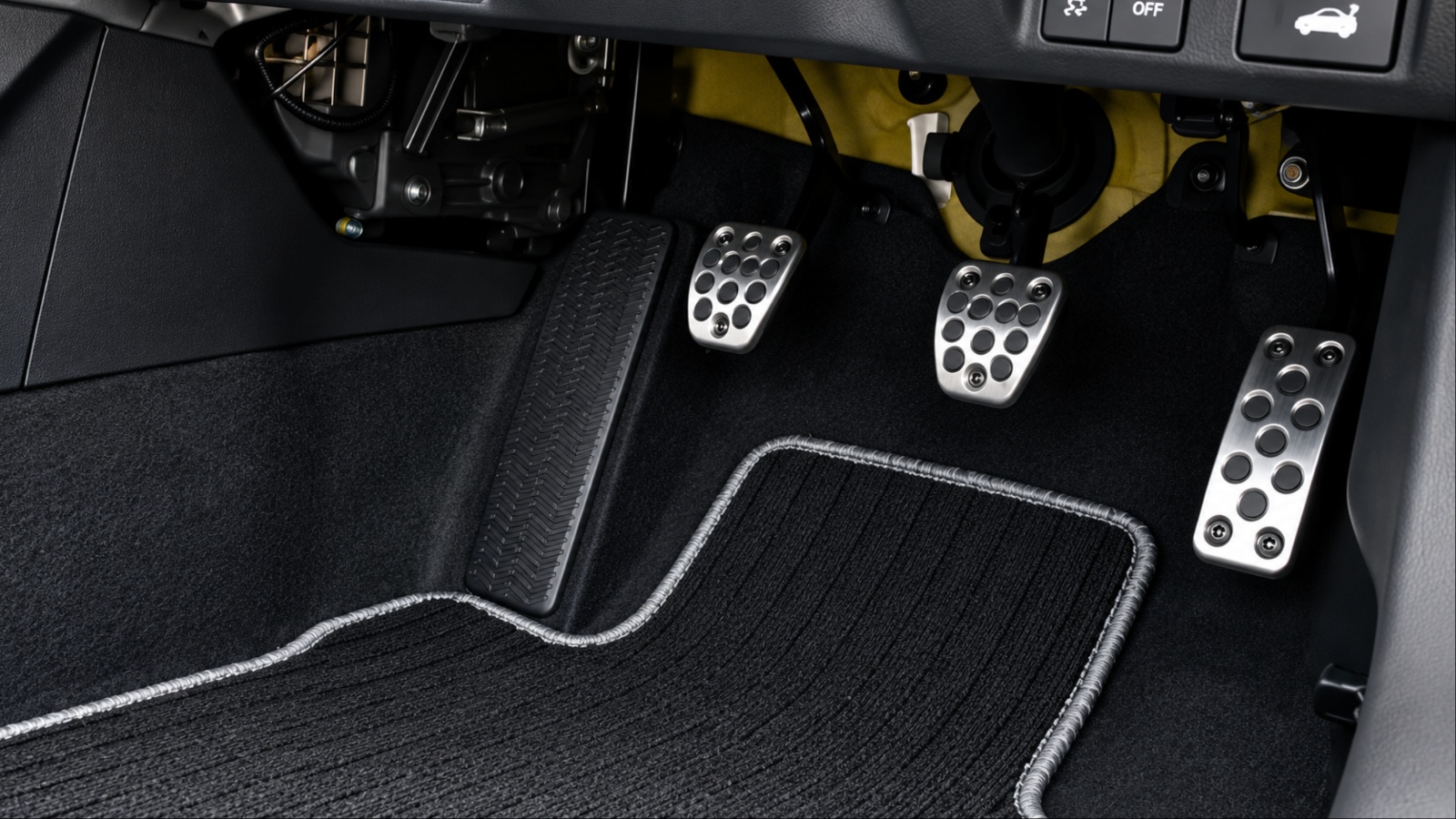 Car pedals and floor mat shown inside a vehicle’s driver footwell