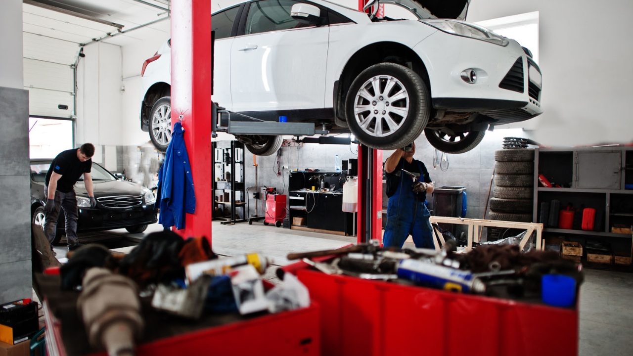Car repair shop technicians service a vehicle raised on a hydraulic lift