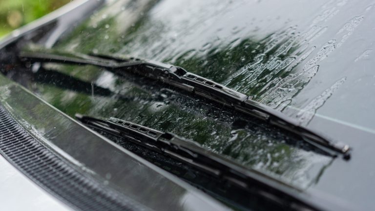 Car windshield wipers clearing rainwater during a wet drive, improving visibility