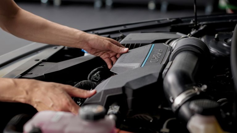 person hands adjusting hybrid engine cover under open hood