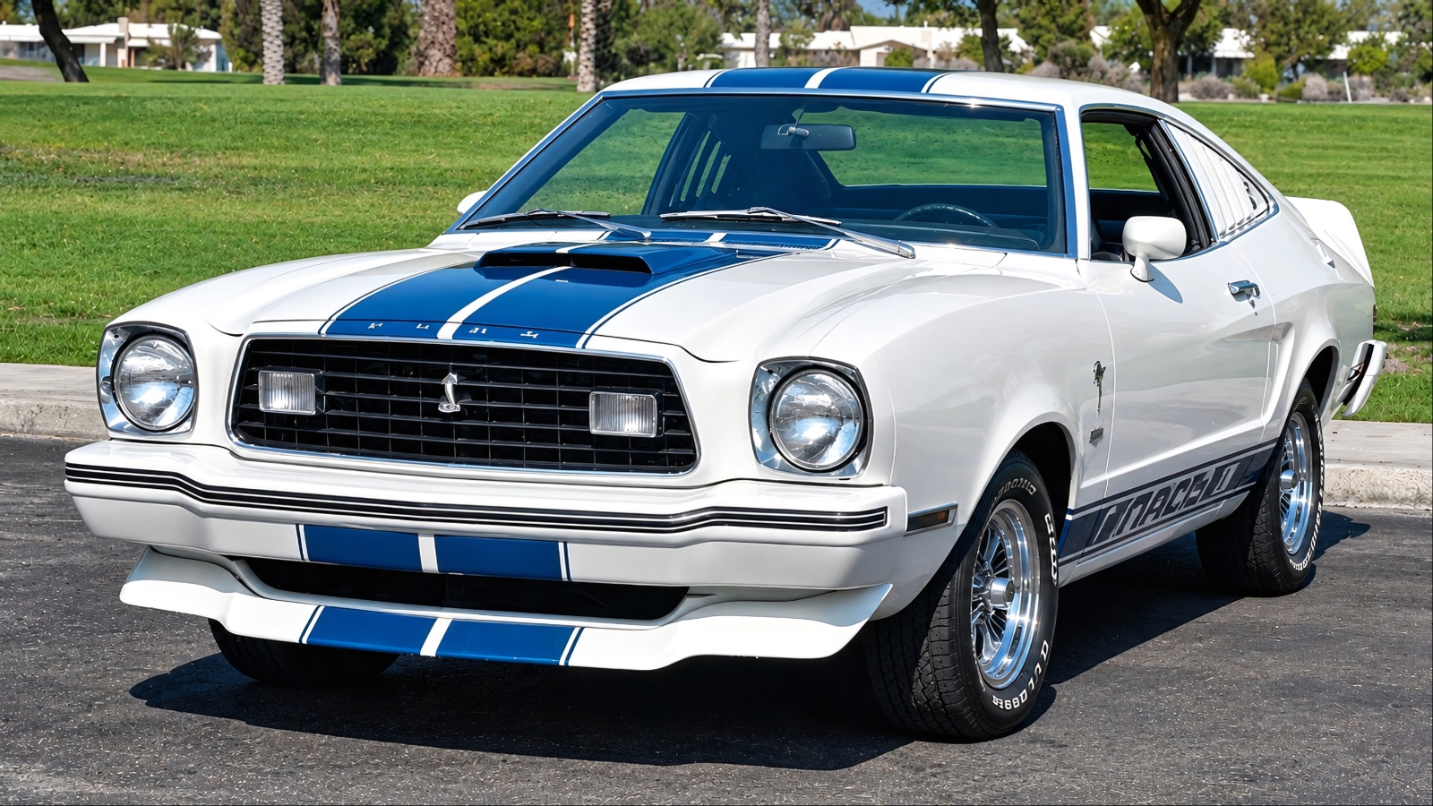 White Ford Mustang II Mach 1 with blue racing stripes, parked outdoors