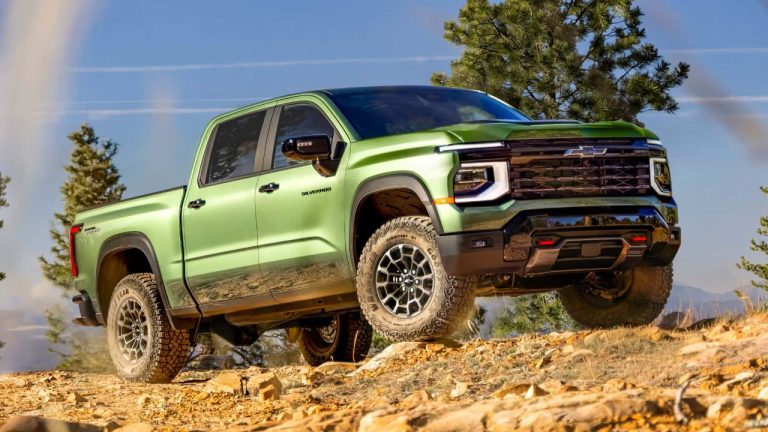 Chevrolet Silverado HD climbing rocky terrain with mountains and trees in the background