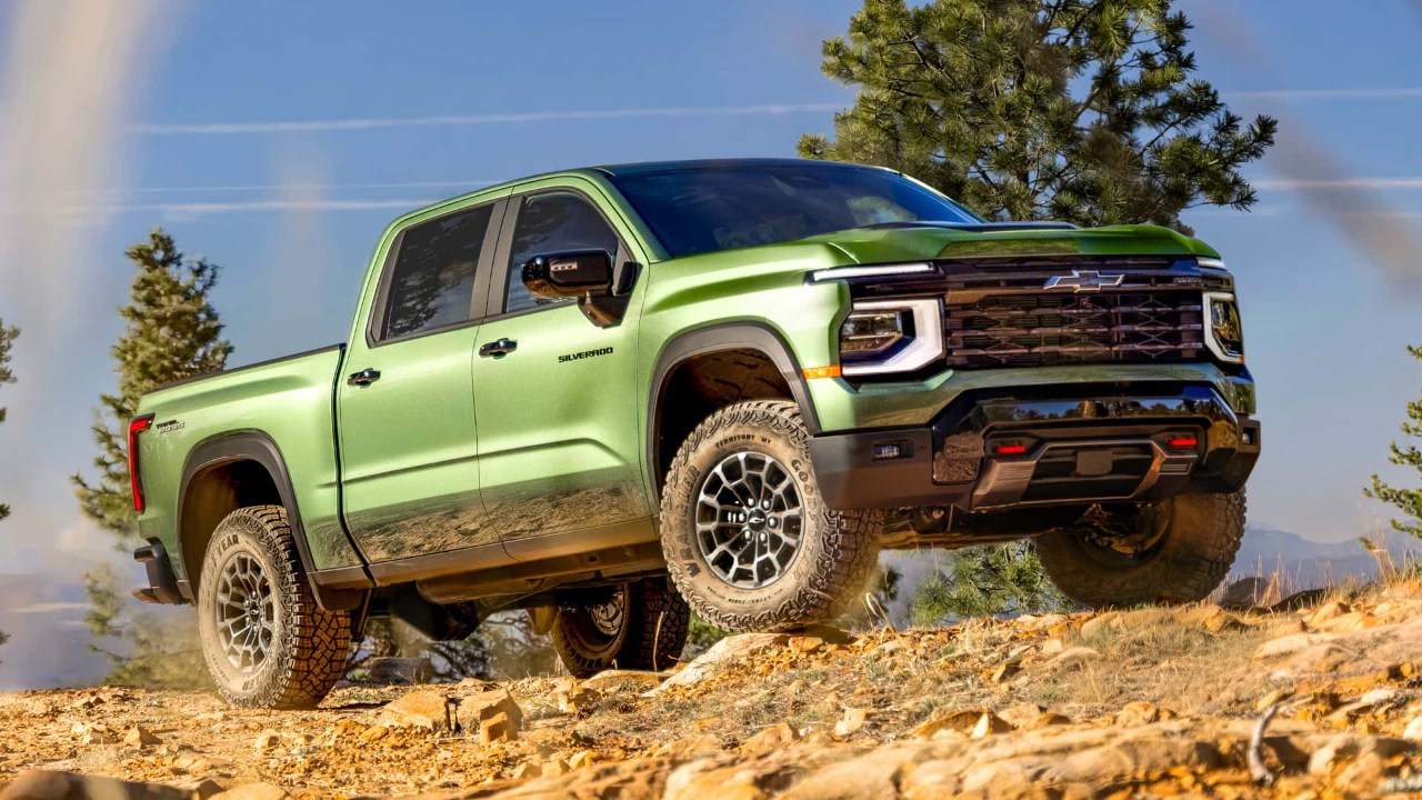 Chevrolet Silverado HD climbing rocky terrain with mountains and trees in the background