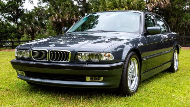 Classic BMW sedan parked on a grassy lawn surrounded by lush trees