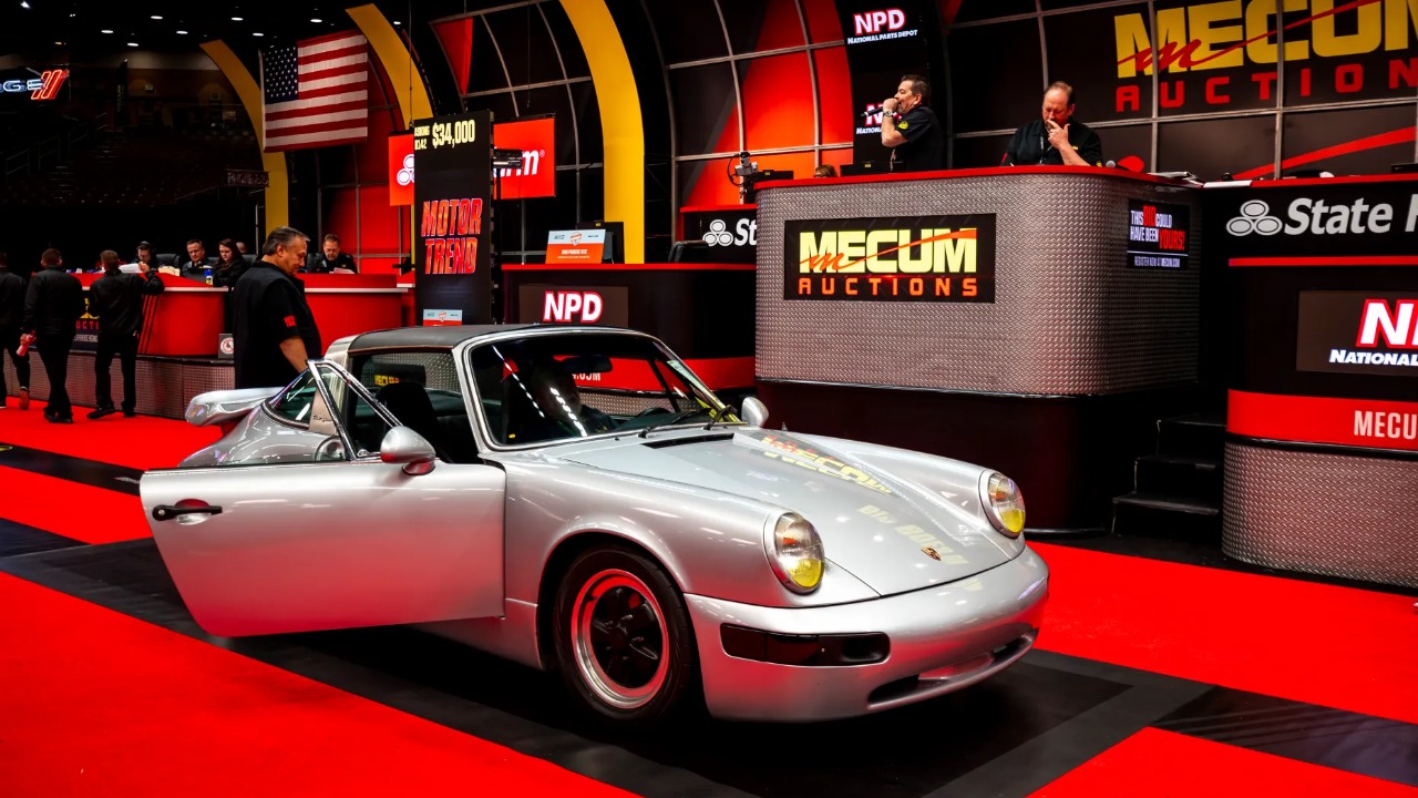 Classic Porsche displayed at Mecum Auctions, surrounded by vibrant auction-stage lighting