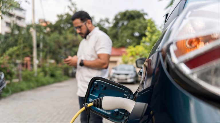 Electric vehicle charging, with the driver waiting nearby