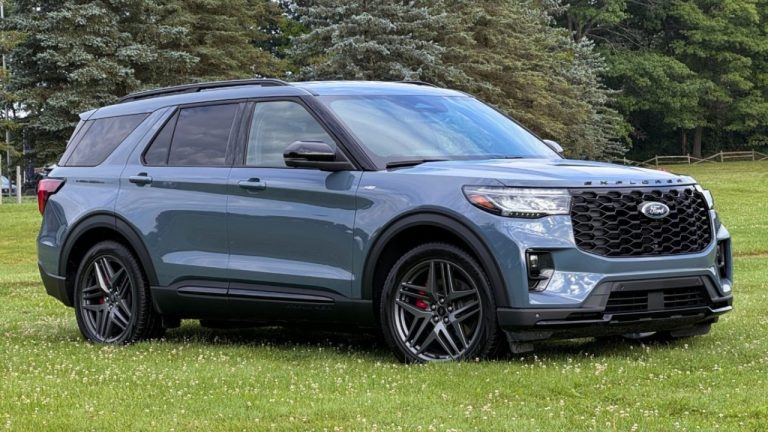 Ford Explorer parked on a grassy field surrounded by dense woodland