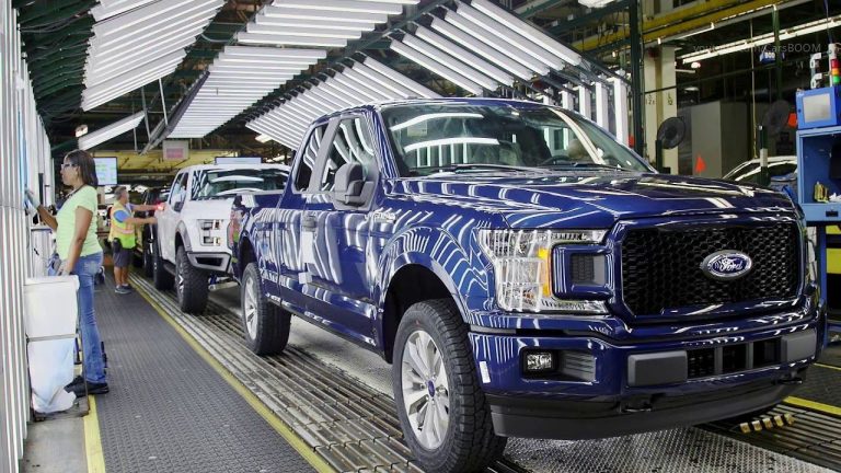 Ford F-150 pickups moving through a busy Michigan assembly plant production line
