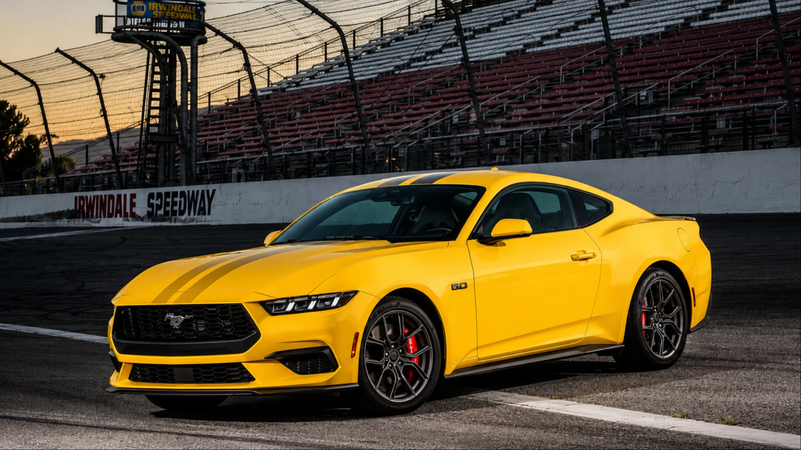 A yellow Ford Mustang photographed on a racetrack beside empty grandstands
