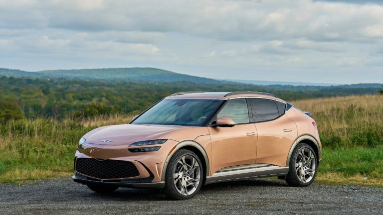 Genesis GV60 parked beside a scenic field with rolling hills and cloudy skies