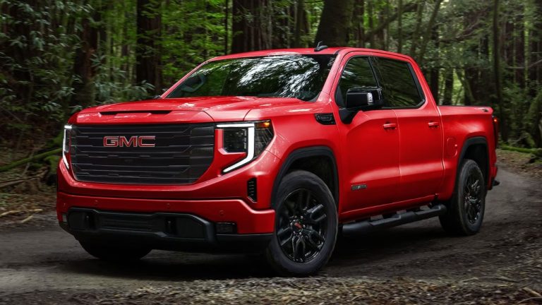 GMC Sierra 1500 tackling a forest trail with rugged styling and bold red paint