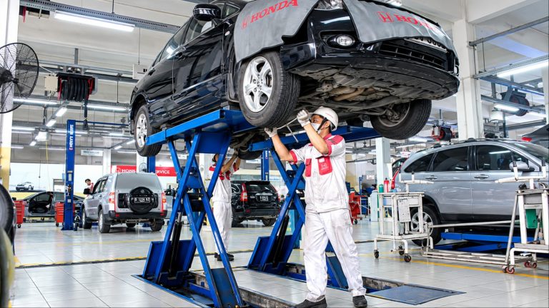 Honda sedan on a service lift undergoing major maintenance at a repair shop after high mileage use