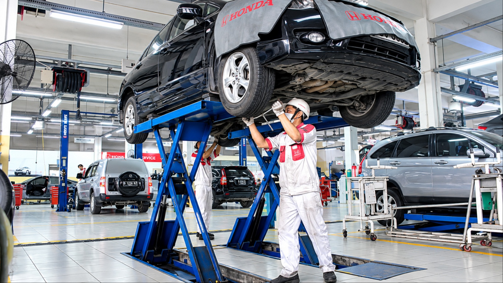 Honda sedan on a service lift undergoing major maintenance at a repair shop after high mileage use