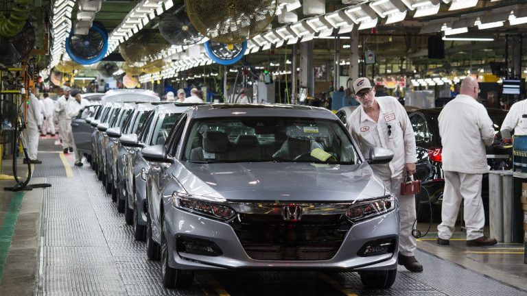 Honda vehicles move along an active automotive assembly line as workers conduct final production checks