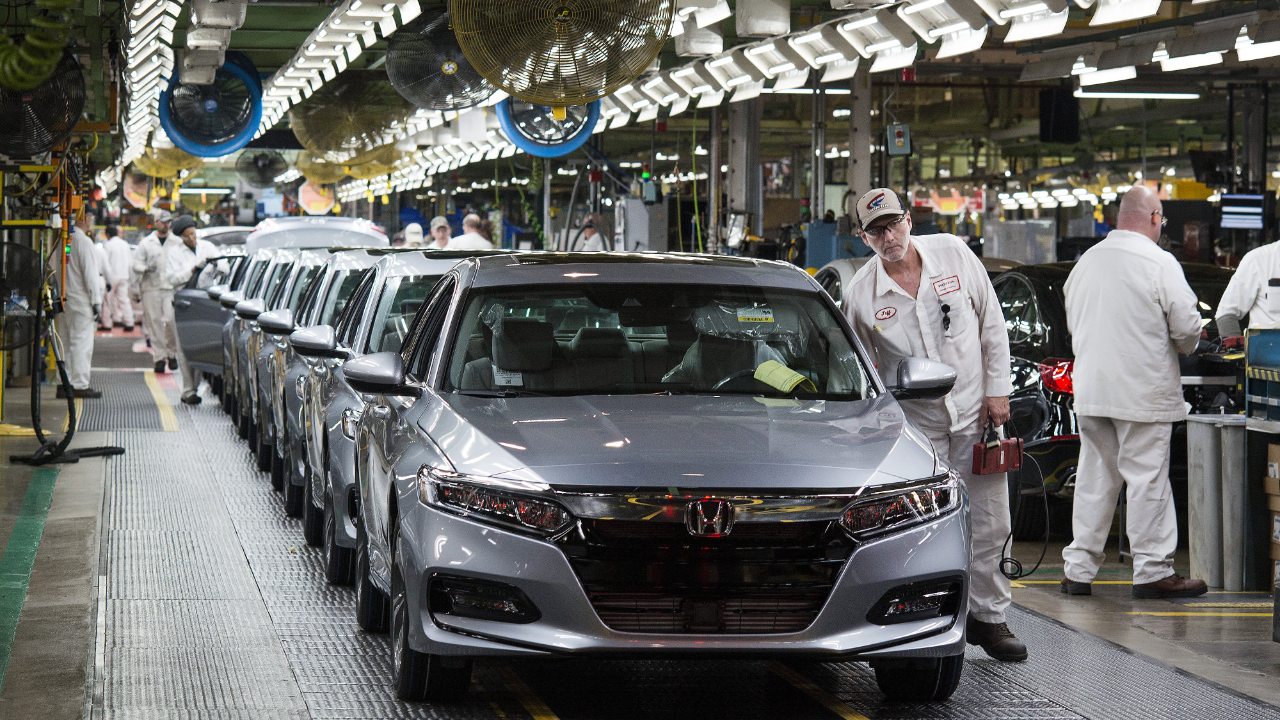 Honda vehicles move along an active automotive assembly line as workers conduct final production checks