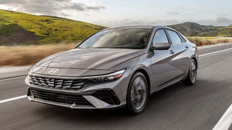 Hyundai Elantra sedan driving along a scenic road through rolling green hills
