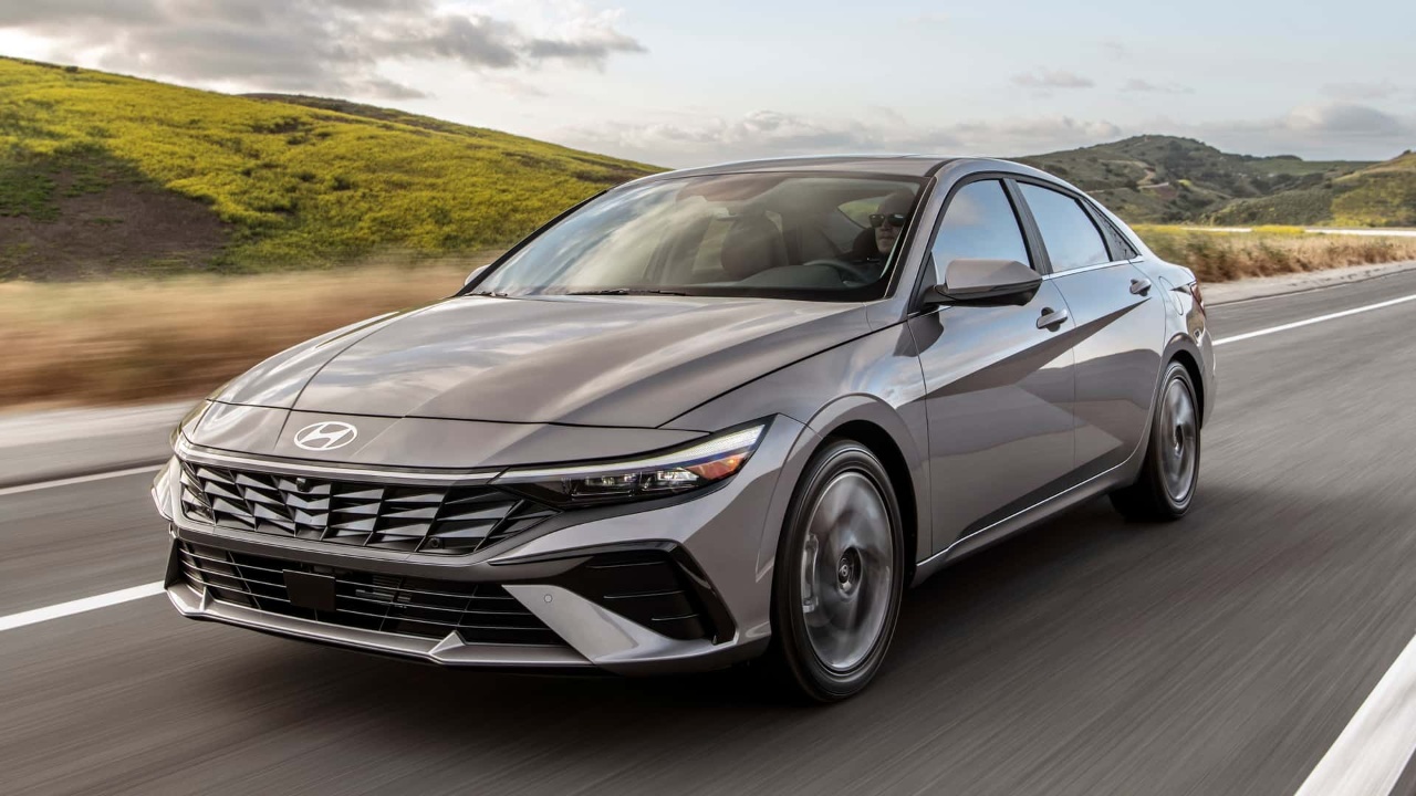 Hyundai Elantra sedan driving along a scenic road through rolling green hills
