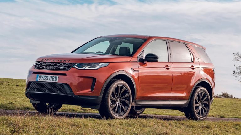 Land Rover Discovery Sport parked on a grassy hillside beneath a bright sky