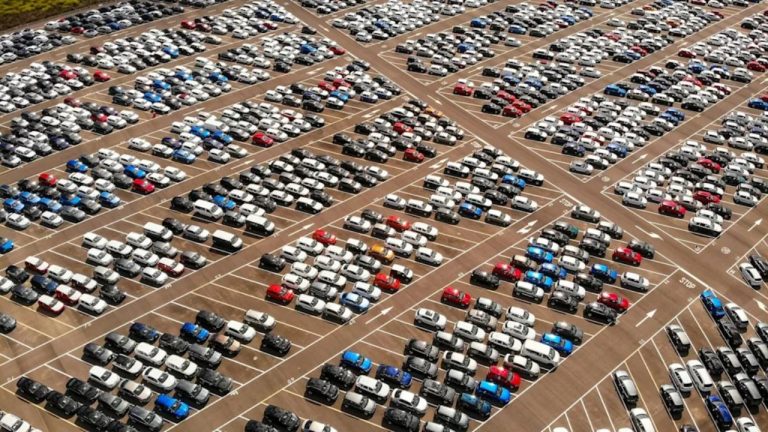 Large dealership lot filled with hundreds of cars arranged in organized rows