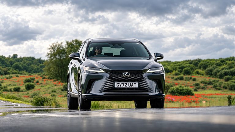 Dark gray Lexus RX SUV driving on wet rural road