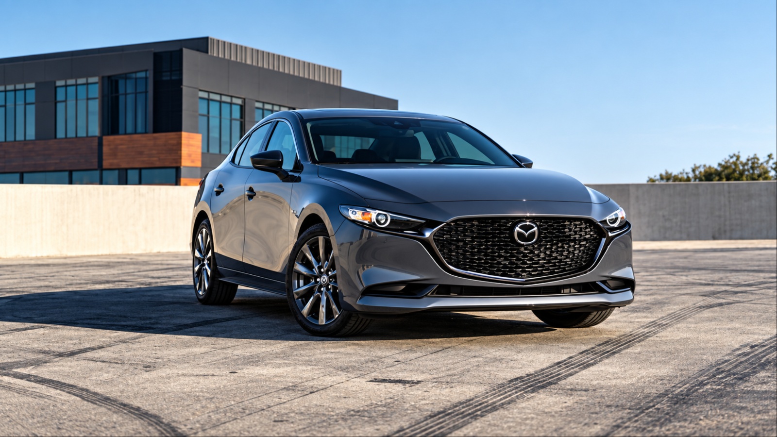 2026 Mazda3 sedan parked outside a modern building under dramatic skies