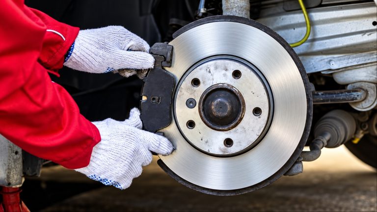 Mechanic replacing worn brake pads on a vehicle’s brake rotor
