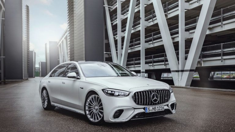 Mercedes-Benz S-Class luxury sedan parked outside a modern multi-story building, shown in a front three-quarter view