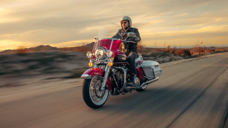 Motorcycle rider cruises along an open desert road at sunset