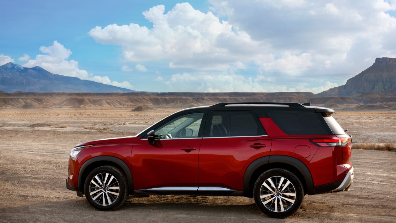 Nissan Pathfinder SUV parked in a rugged desert landscape beneath dramatic mountain scenery