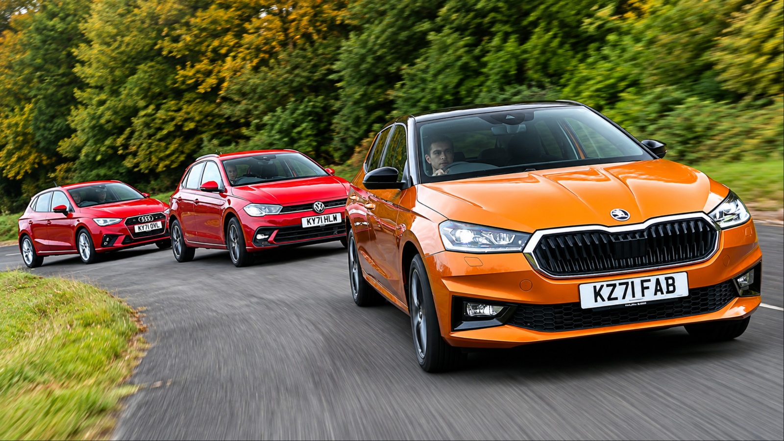 Orange Skoda Fabia leads red Volkswagen Polo and Audi A1 on a road