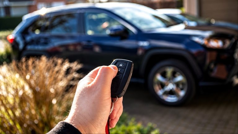 Person holding car key fob in front of black SUV