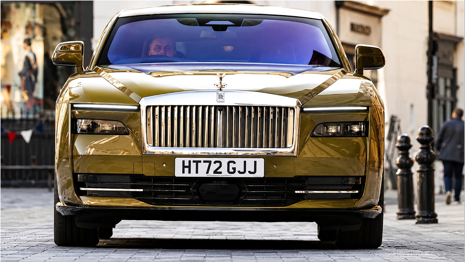 Gold Rolls-Royce Spectre front view driving on city street