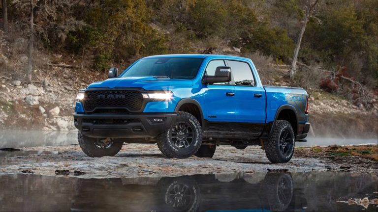 Ram 1500 Rebel parked on rocky terrain beside a calm woodland stream