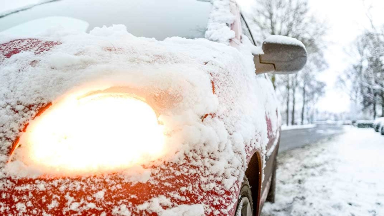 Snow-covered car struggles through freezing conditions on a quiet winter road