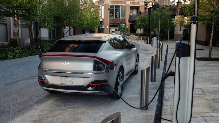 Silver Kia EV6 electric car plugged into charging station outdoors