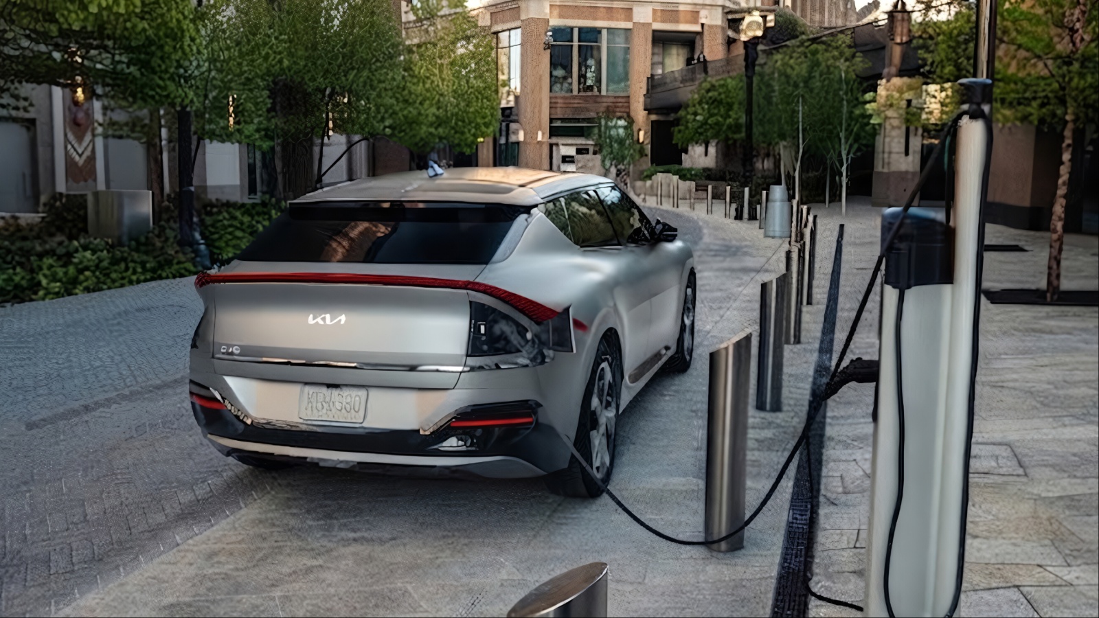 Silver Kia EV6 electric car plugged into charging station outdoors