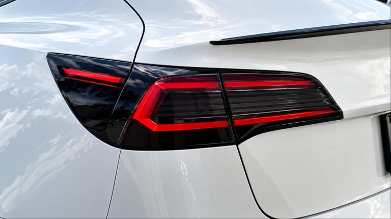 Close-up of white car rear featuring modern tinted red taillights