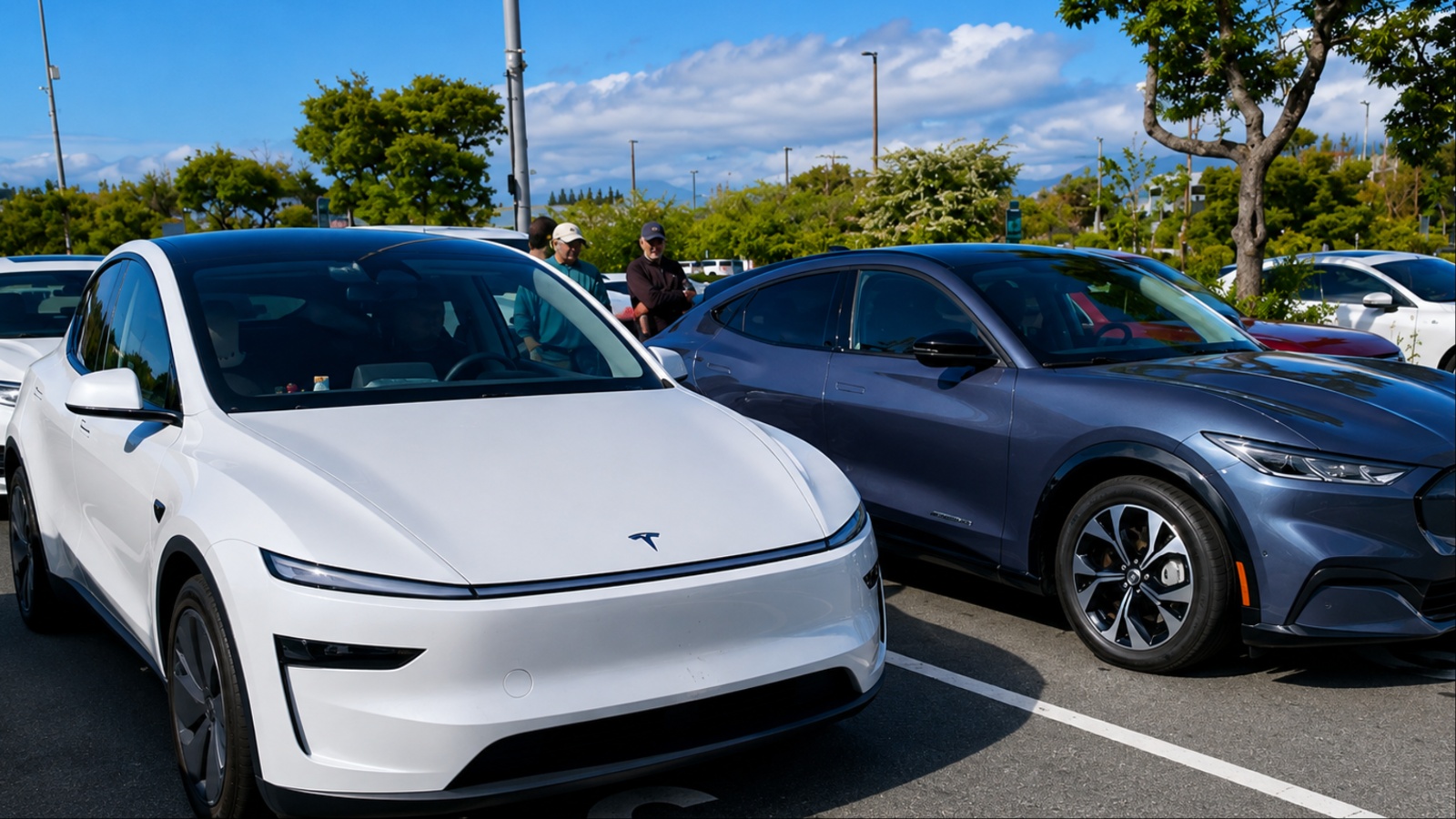 Tesla and Ford electric vehicles parked together under bright daylight