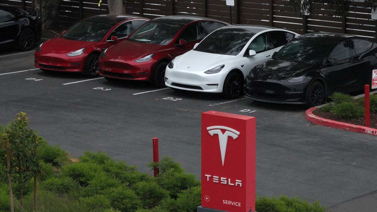 Tesla vehicles parked outside a service center, showing several Model 3 and Model Y cars