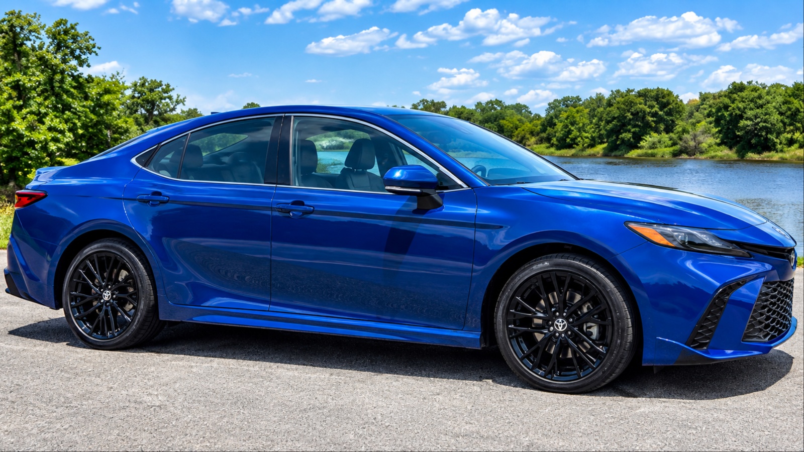 A blue Toyota Camry is standing on a road on a sunny day
