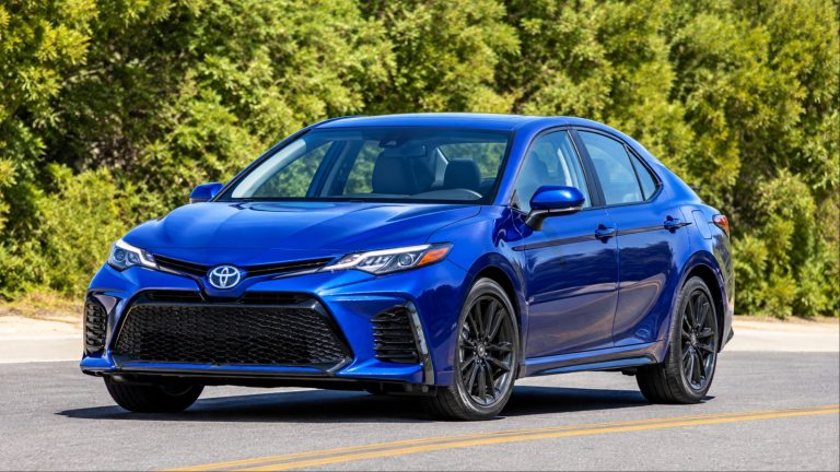 Blue Toyota sedan with black wheels on sunny road