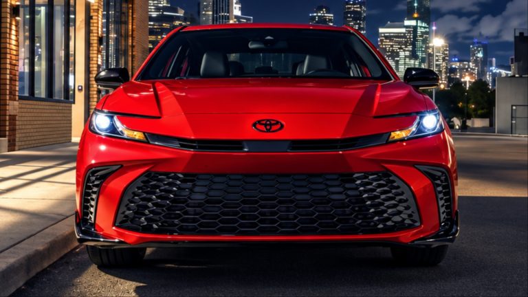 Front view of red Toyota sedan with headlights on at night