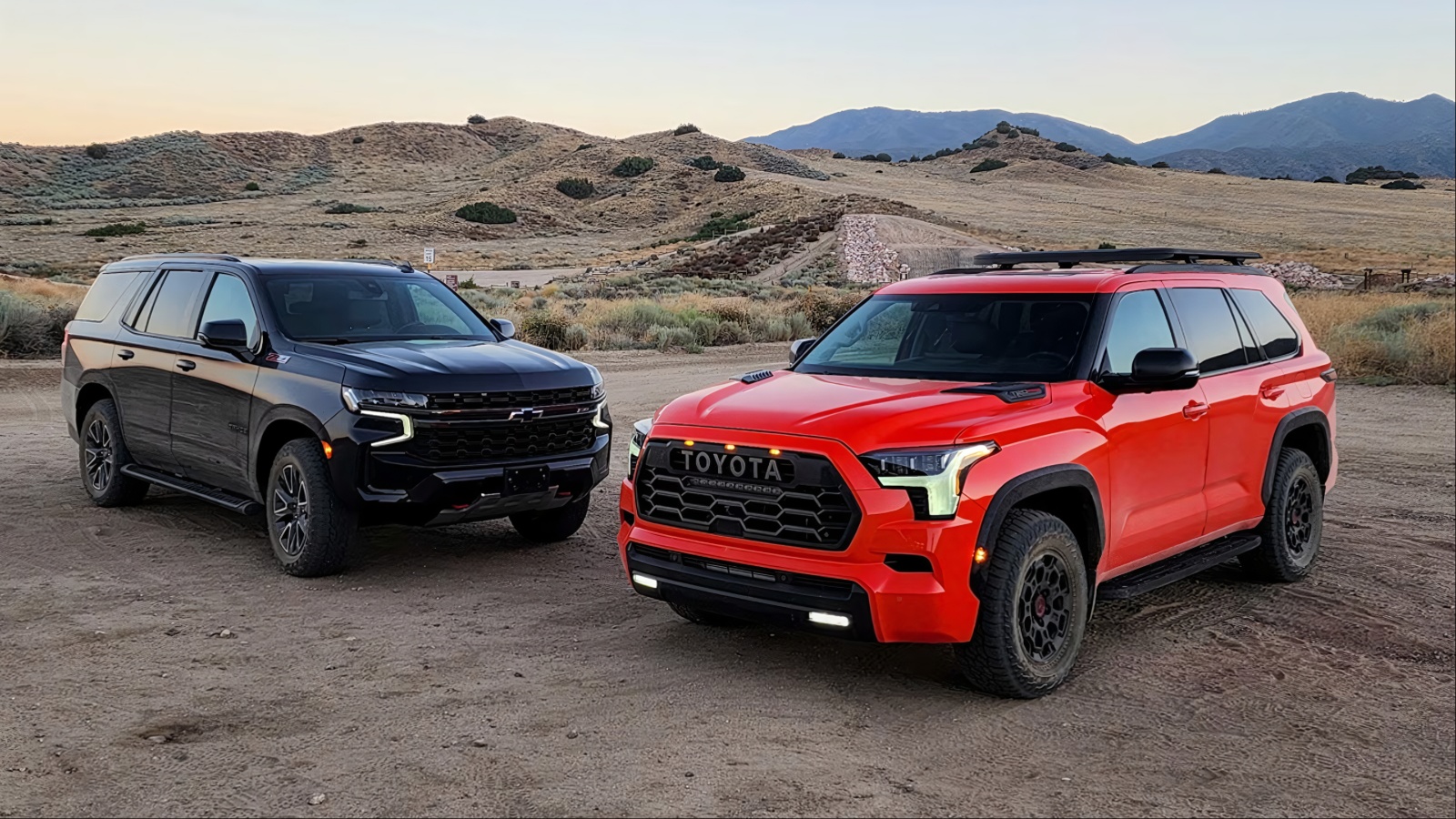 Black Chevrolet SUV and red Toyota Sequoia on dirt road