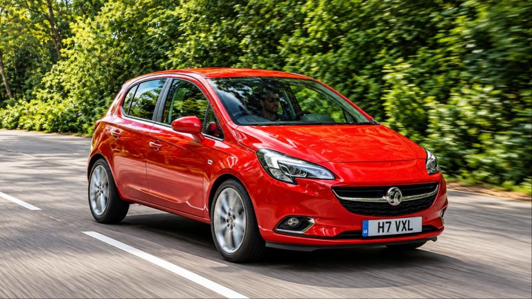 Bright red Vauxhall Corsa hatchback driving on tree-lined road