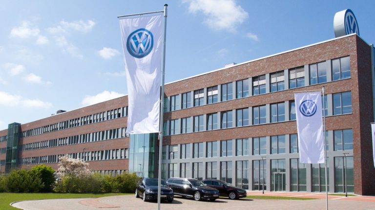 Volkswagen facility displaying brand flags outside its modern brick headquarters
