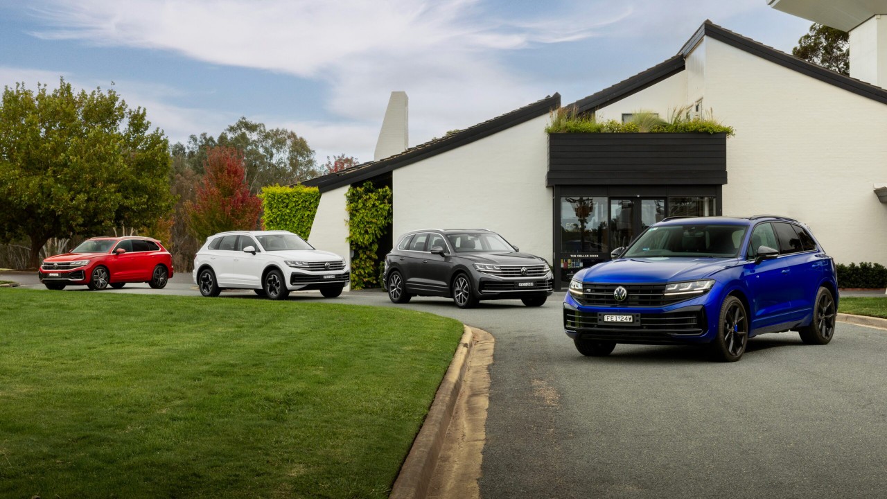 Volkswagen SUVs parked outside a modern building, with a blue Touareg in the foreground
